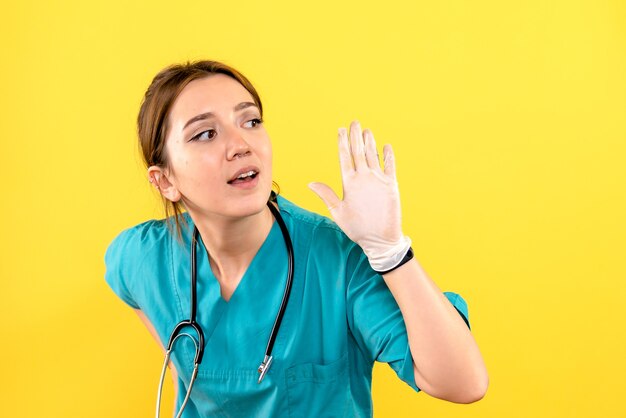 Vorderansicht des weiblichen Tierarztes, der Handschuhe auf gelber Wand trägt