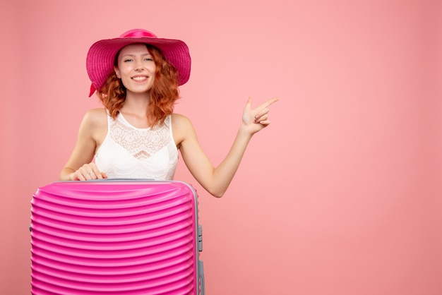 Vorderansicht des weiblichen Touristen mit rosa Tasche an der rosa Wand