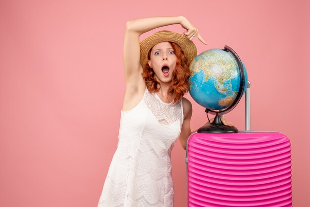 Vorderansicht des weiblichen Touristen mit rosa Tasche an der rosa Wand