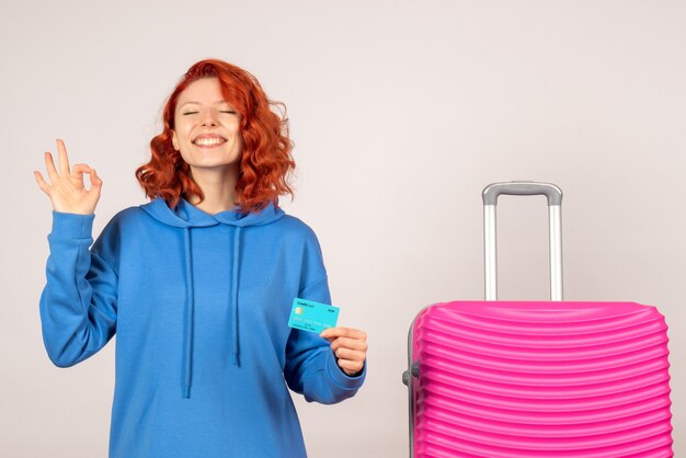 Vorderansicht des weiblichen Touristen mit rosa Tasche auf weißer Wand