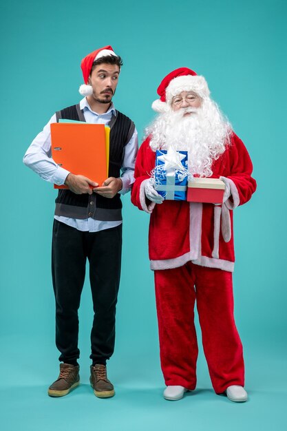 Vorderansicht des Weihnachtsmannes mit jungem Mann und präsentiert auf blauer Wand