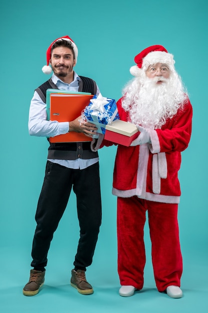 Vorderansicht des Weihnachtsmannes mit jungem Mann und präsentiert auf blauer Wand