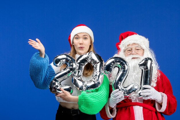 Vorderansicht des Weihnachtsmanns zusammen mit der jungen weiblichen Holdingfigur an der blauen Wand