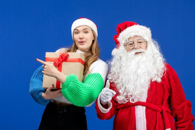 Vorderansicht des Weihnachtsmanns zusammen mit einer Frau, die an der blauen Wand präsent ist