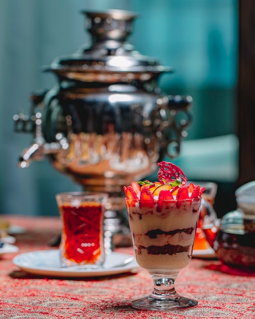 Vorderansicht Dessert Tiramisu in einem Glas mit geschnittenen Erdbeeren und Apfel und einem Glas Tee