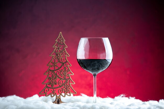 Vorderansicht ein Glas Wein aus Holz Weihnachtsdekoration auf dunkelrotem Hintergrund