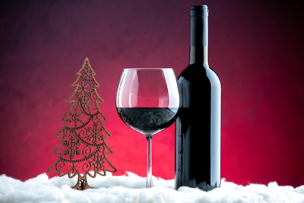Vorderansicht ein Glas Wein Weinflasche auf dunkelrotem Hintergrund