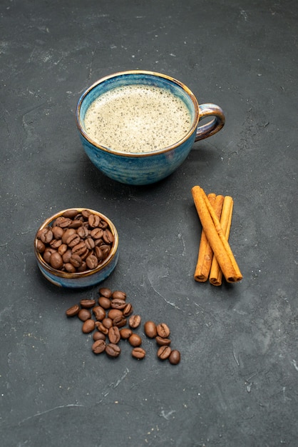 Vorderansicht eine Tasse Kaffeeschale mit Kaffeebohnensamen-Zimtstangen auf dunklem, isoliertem Hintergrund