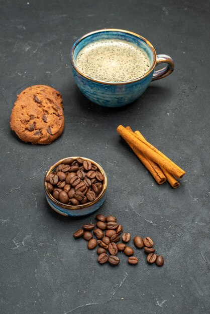 Vorderansicht eine Tasse Kaffeeschale mit Kaffeesamen Zimtstangen Kekse auf dunklem, isoliertem Hintergrund