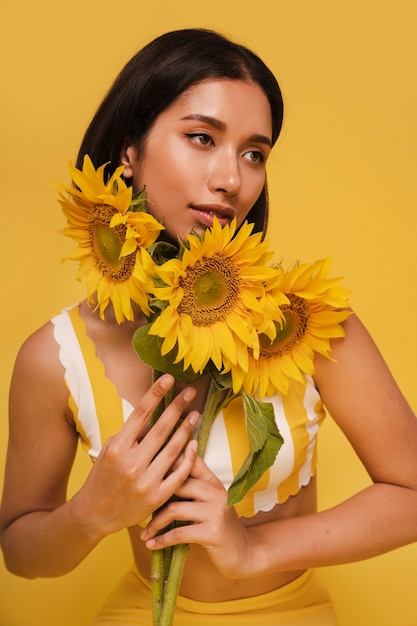 Vorderansicht einer Frau, die mit Sonnenblumen posiert