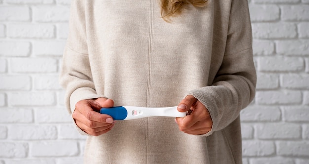 Kostenloses Foto vorderansicht einer frau mit positivem schwangerschaftstest