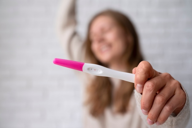 Kostenloses Foto vorderansicht einer frau mit positivem schwangerschaftstest