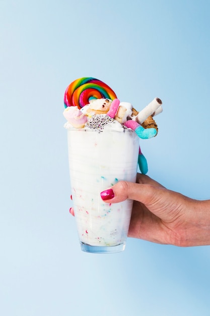 Vorderansicht einer Hand, die ein Glas mit Milchshake durchlöchert