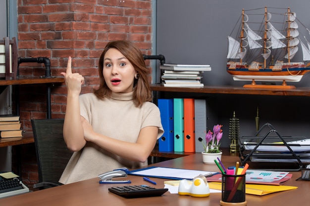 Vorderansicht einer hübschen Frau, die mit einer Idee überrascht, die im Büro arbeitet