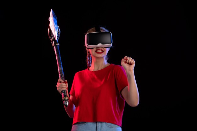 Vorderansicht einer hübschen Frau, die vr mit einer dunklen Streitaxt spielt