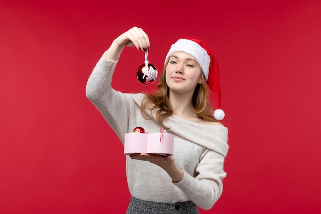 Vorderansicht einer jungen Frau, die ein Geschenk voller Spielzeug auf Rot hält