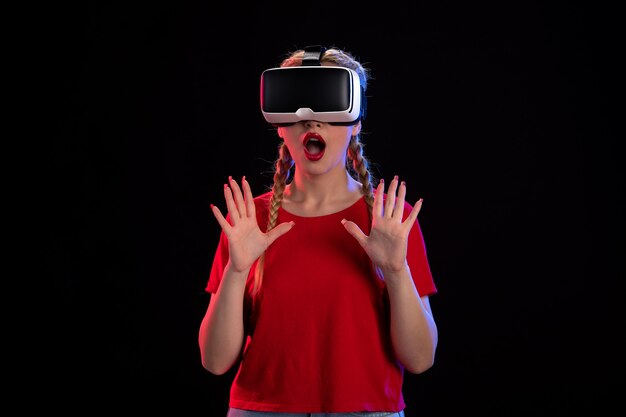 Vorderansicht einer jungen Frau, die virtuelle Realität auf dunklem visuellem Ultraschall spielt