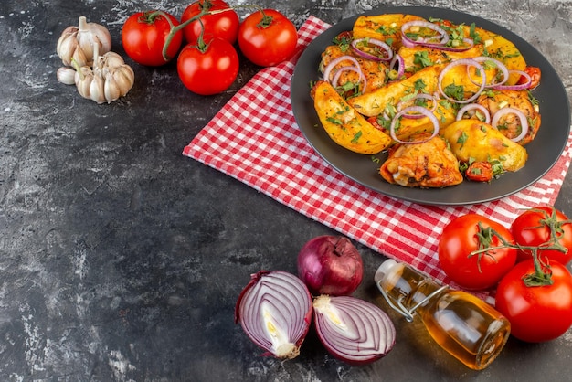 Kostenloses Foto vorderansicht eines leckeren hühnergerichts mit kartoffeln und gemüse auf einem gefalteten, rot gestreiften handtuch auf einem dunklen farbtisch