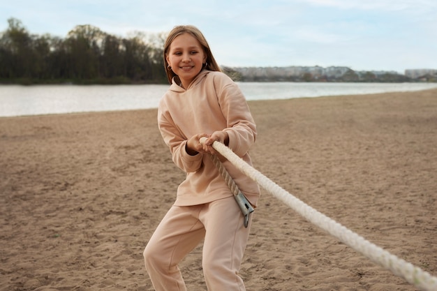 Kostenloses Foto vorderansicht eines mädchens, das am strand tauziehen spielt