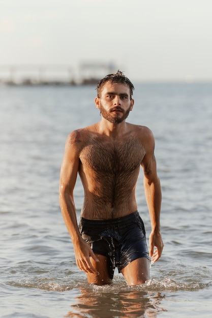 Kostenloses Foto vorderansicht eines mannes mit behaarter brust am meer