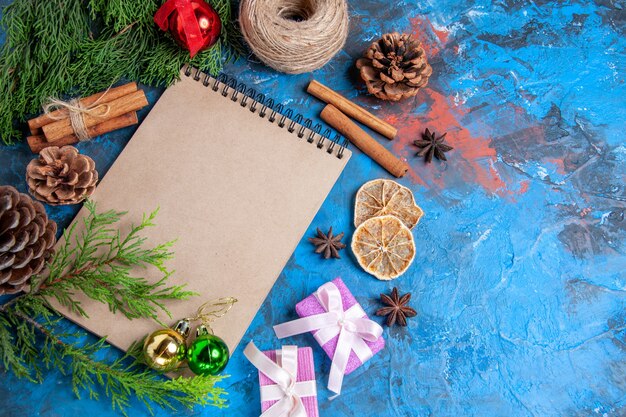 Vorderansicht eines Notebook-Kieferzweiges Tannenzapfen-Sternanis-Strohfaden auf blauem Hintergrund freier Raum