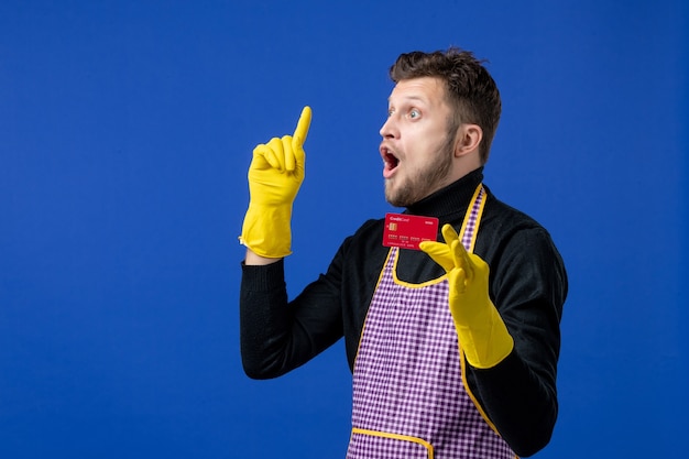 Vorderansicht eines überraschten jungen Mannes, der eine Karte hält, die auf die Decke an der blauen Wand zeigt?