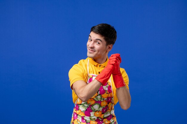Vorderansicht eines zufriedenen Haushältermanns, der seine Hände zusammenhält und auf blauer Wand steht