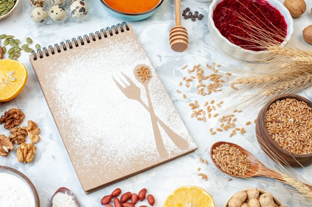 Vorderansicht einfacher Notizblock mit Mehl-Eier-Gelee und verschiedenen Nüssen auf weißem Hintergrund Fruchtnuss-Zucker-Farbkuchen-Foto süßer Kuchenteig