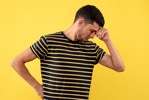 Vorderansicht enttäuschte jungen Mann im schwarzen und weißen gestreiften gelben isolierten Hintergrund des T-Shirts