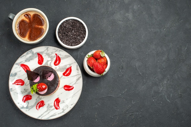 Vorderansicht Erdbeer-Käsekuchen auf weißen ovalen Tellerschalen mit Erdbeeren und Schokolade eine Tasse Kaffee auf dunklem Hintergrund Freiraum