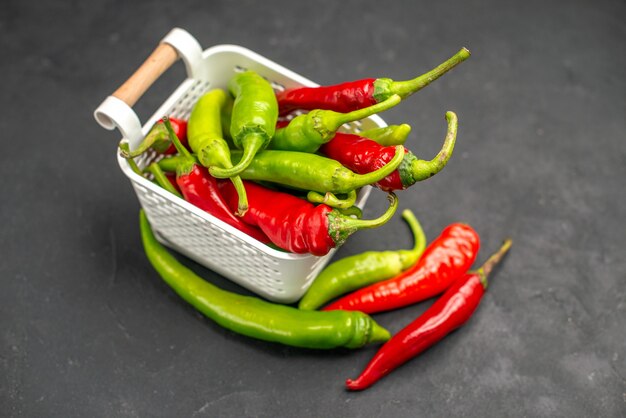 Vorderansicht farbige würzige Paprika im Korb auf dunklem Hintergrund Essen Farbe Foto Salat Gesundheit