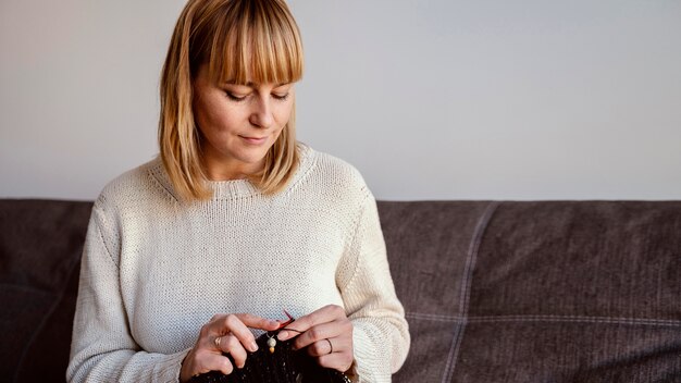 Vorderansicht Frau, die auf dem Sofa näht und sitzt