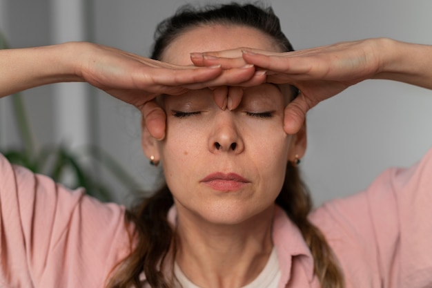 Kostenloses Foto vorderansicht frau, die gesichtsyoga praktiziert