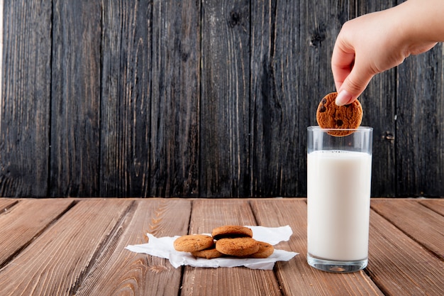 Vorderansicht Frau Dunks Haferkekse auf Transparentpapier mit Glas Milch auf einem hölzernen Hintergrund