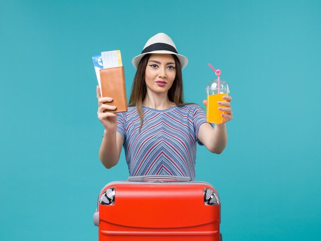 Vorderansicht frau im urlaub, die frischen saft und tickets auf blauem schreibtisch trip sommerreise reise urlaub meer hält