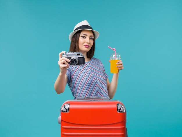 Vorderansicht Frau im Urlaub hält Saft und Kamera auf einer blauen Hintergrundreise Sommerreise Reise Urlaub Meer