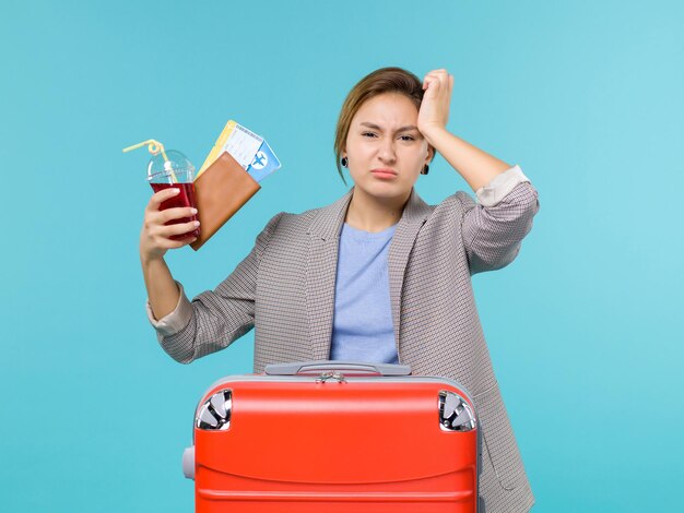 Vorderansicht Frau im Urlaub hält Saft und Tickets auf dem blauen Hintergrund Reiseflug Urlaubsreise Reise Meer