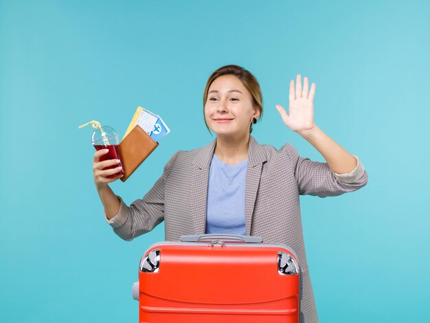 Vorderansicht Frau im Urlaub hält Saft und Tickets winken jemandem auf blauem Hintergrund Reise Urlaubsreise Reise Wasserflugzeug