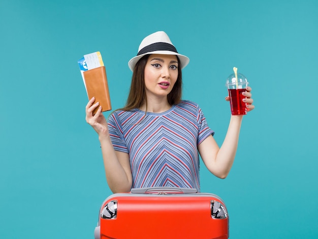 Vorderansicht Frau im Urlaub hält Tickets und roten Saft auf dem blauen Hintergrund Seereise Reise weiblichen Urlaub