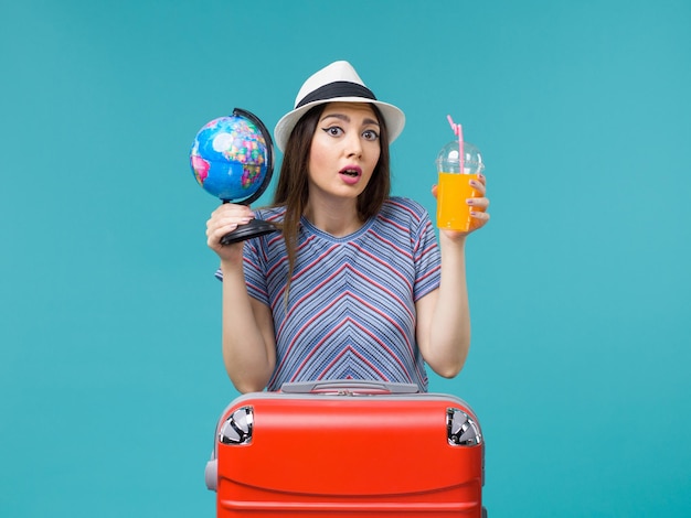 Kostenloses Foto vorderansicht frau im urlaub halten saft und globus auf blauem hintergrund seereise reise urlaub sommerreise
