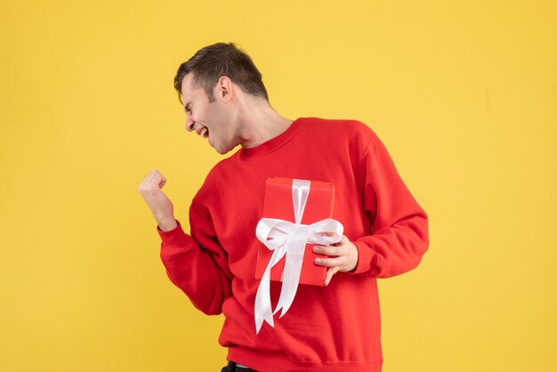 Vorderansicht freute sich junger Mann mit rotem Pullover auf gelb stehend