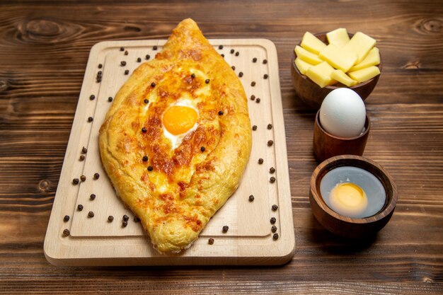 Vorderansicht frisch gebackenes Brot mit gekochtem Ei auf braunem Schreibtisch Teignahrung Frühstück backen Brötchen Mahlzeit