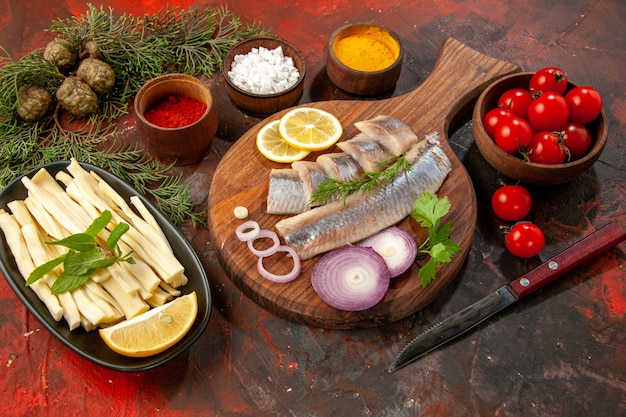 Vorderansicht frisch geschnittener Fisch mit Gewürzen Tomaten und Käse auf dunklen Meeresfrüchten Farbfoto Snack Fleisch reifen Salat