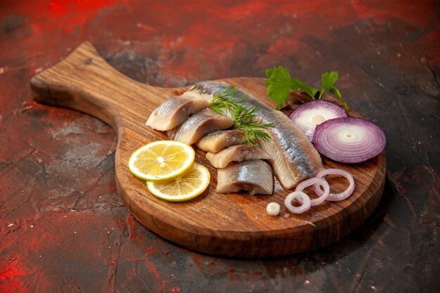 Vorderansicht frisch geschnittener Fisch mit Zwiebelringen und Zitrone auf dunklem Fleisch-Meeresfrüchte-Snack-Farbfoto