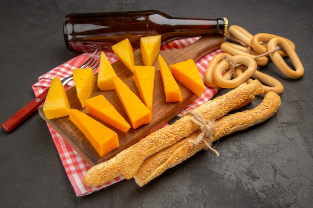 Vorderansicht frisch geschnittener Käse mit Brötchen und Crackern auf dunkelgrauer Farbe Mahlzeit Foto Frühstück Cips Essen knusprig