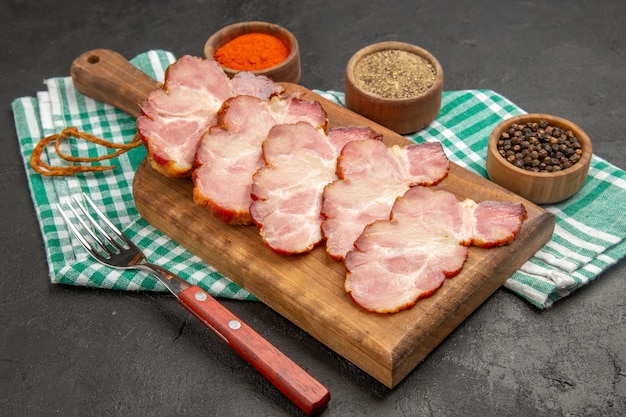 Vorderansicht frisch geschnittener Schinken mit Gewürzen auf dunkelgrauem Fleisch rohes Foto