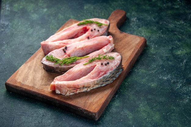 Vorderansicht frische Fischscheiben auf dunkelblauer Oberfläche Lebensmittel Gesundheit Pfeffer Farbe Mahlzeit Salat Diät Meeresfrüchte Meerwasser Fisch