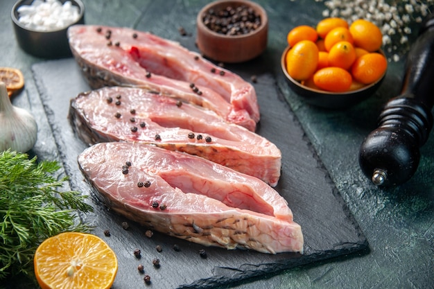 Vorderansicht frische Fischscheiben mit Pfeffer auf einer dunklen Oberfläche Fleisch rohe Mahlzeit Wasser Foto Ozean Meeresfrüchte Farbe Abendessen