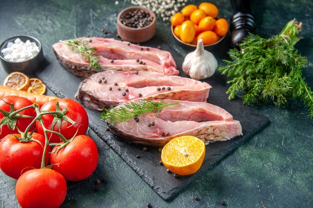 Vorderansicht frische Fischscheiben mit Pfeffergrün und Gemüse auf einer dunklen Oberfläche Ozeanfleisch Rohmehl Wasser Foto Meeresfrüchte Farbe Abendessen