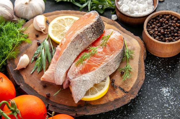 Vorderansicht frische fischscheiben mit tomaten und zitronenscheiben auf dunkler roher farbe meeresfrüchtegericht foto fleischessen